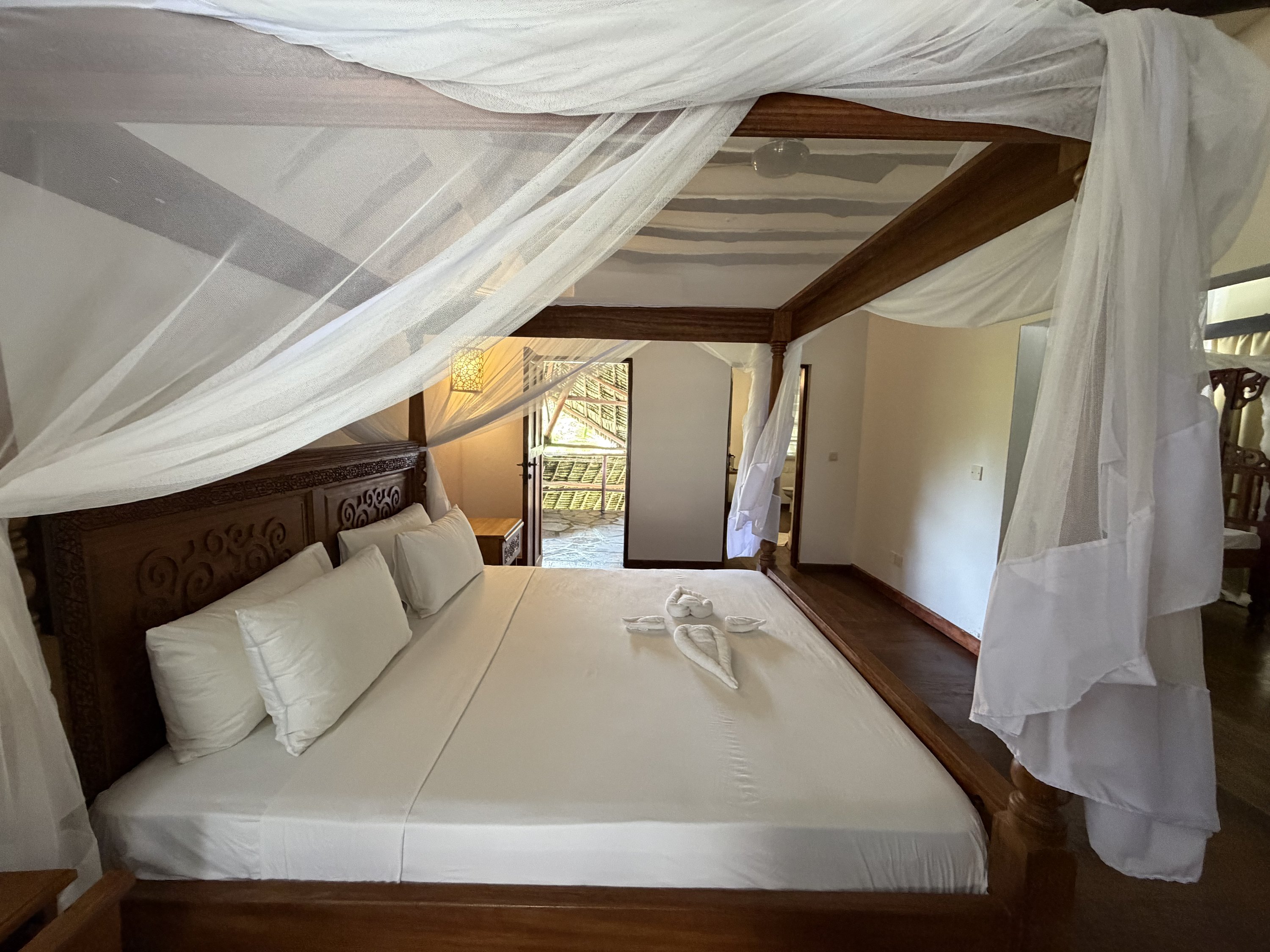 Master bedroom with carved four-poster bed and mosquito net